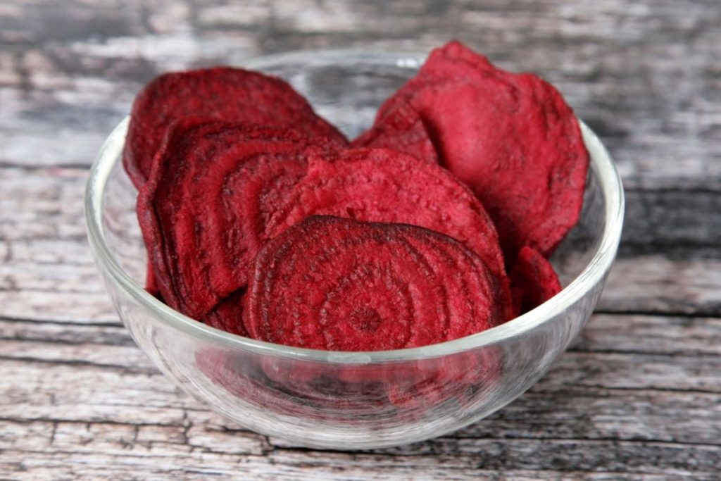Beet chips in a bowl on a table.