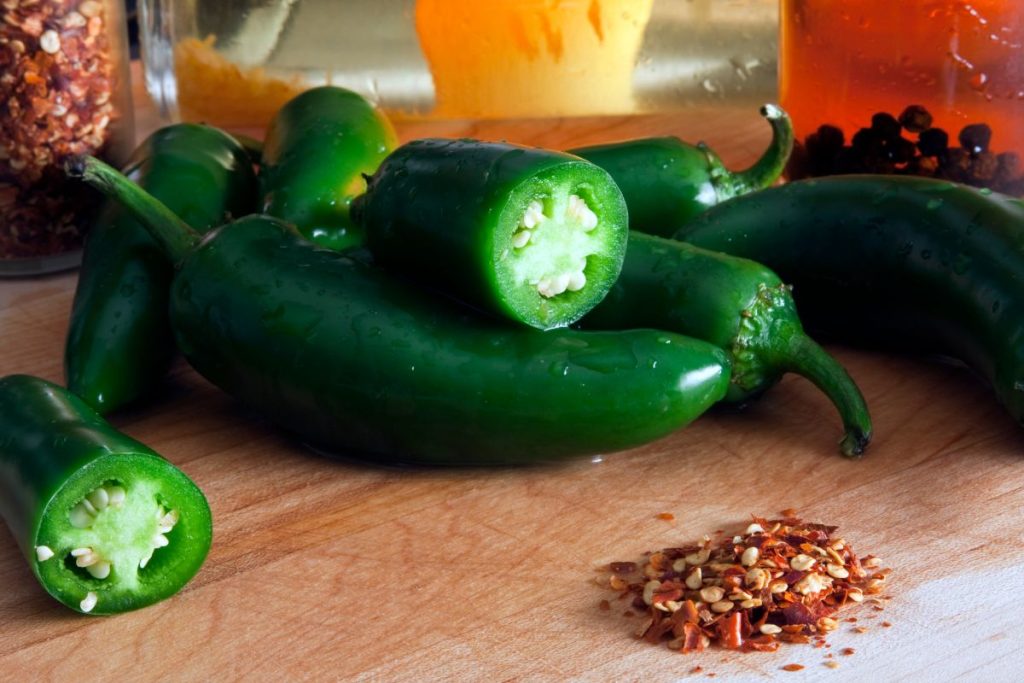 Jalapenos on a table with a pile of jalapenos spice.