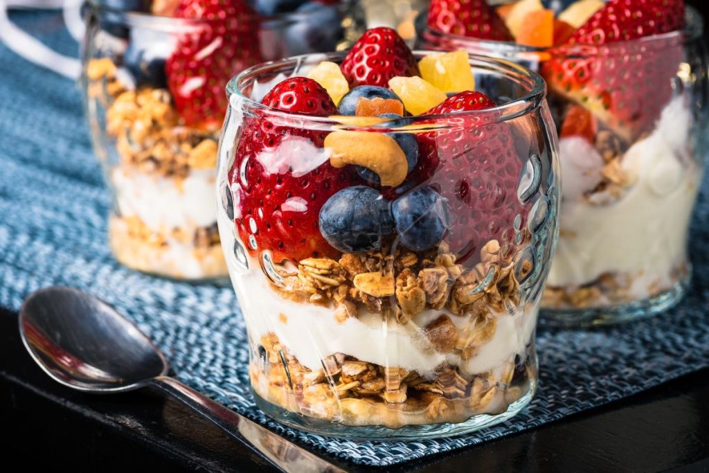 Fresh fruit, granola, and yogurt parfait with sprinkled pieces of dried pineapple