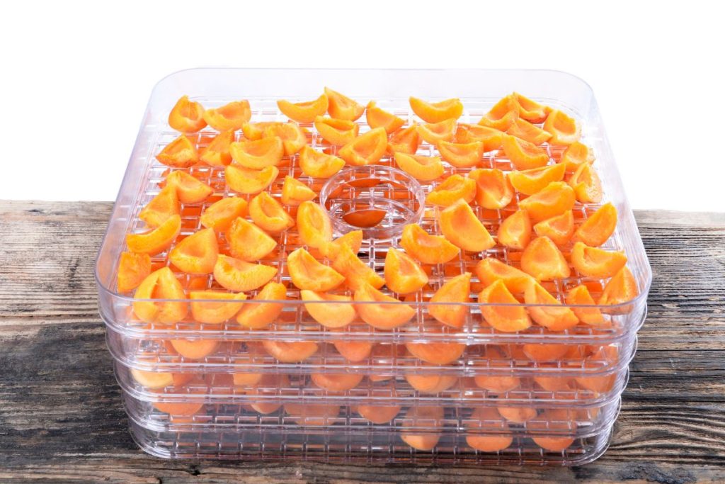 Quartered apricot pieces in food dehydrator trays