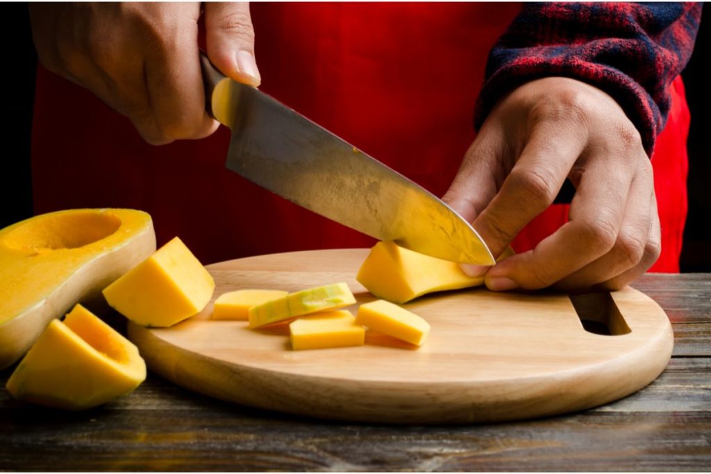 Person cutting thin and even slices of butternut squash