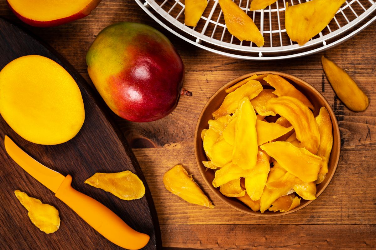 dried mango pieces next to food dehydrator