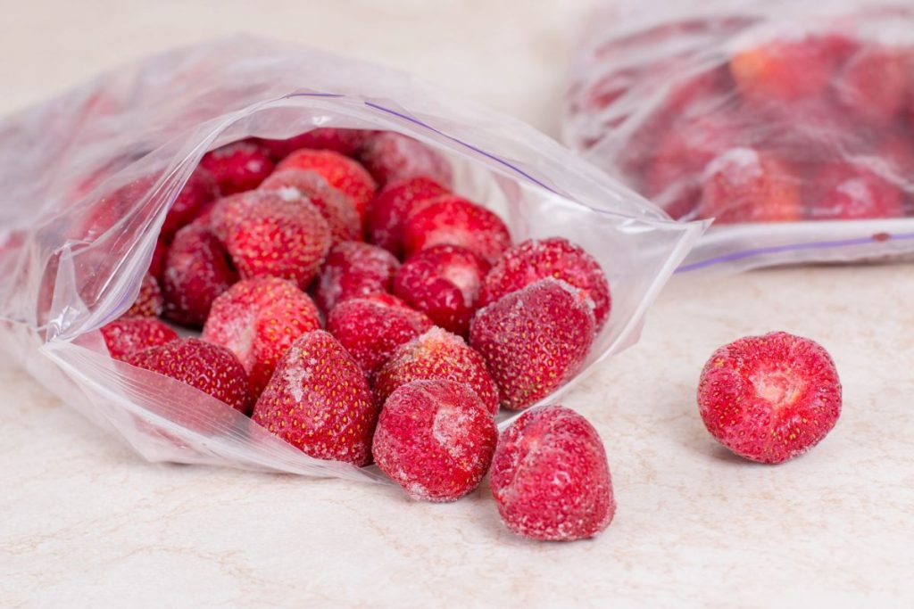 Opened freezer bag full of frozen strawberries
