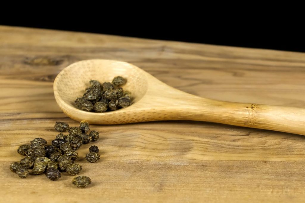 Dried papaya seeds on a wooden spoon