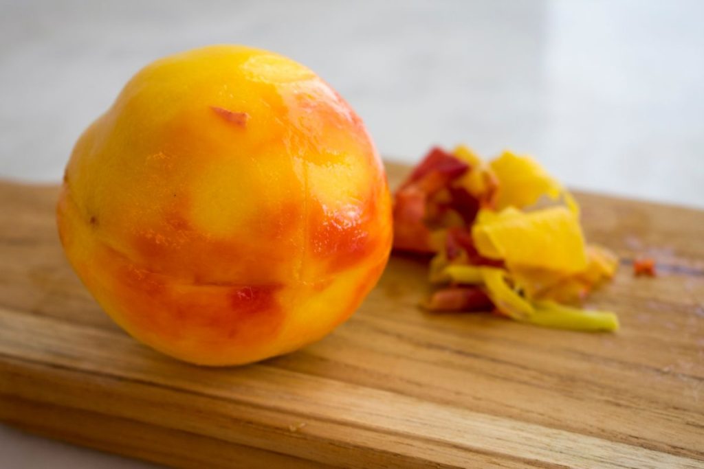 Blanched and peeled peach on a cutting board