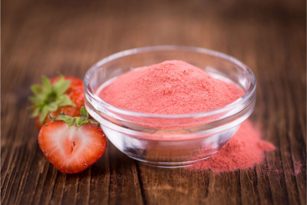 Bowl of strawberry powder next to fresh strawberries