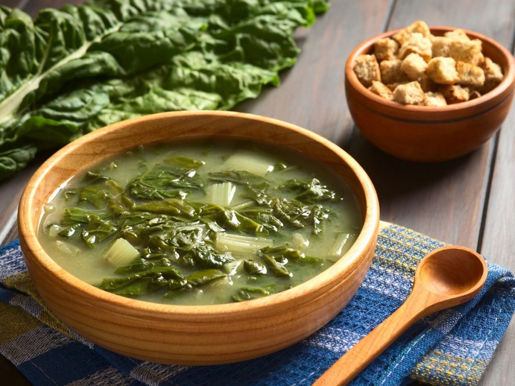 Bowl of Swiss chard soup with a side bowl of croutons