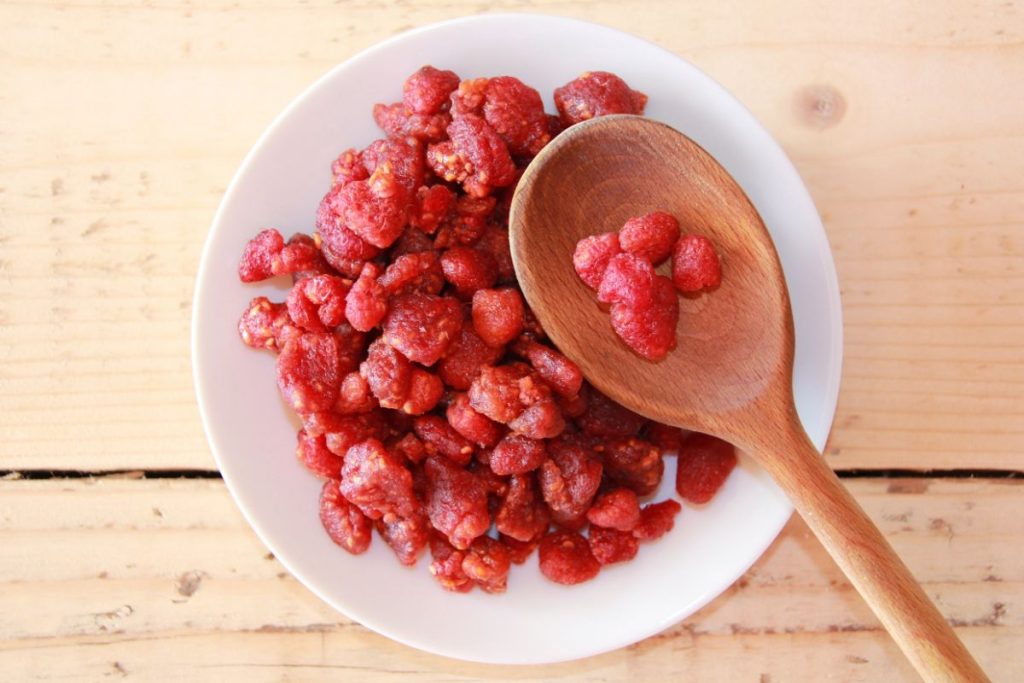 Dehydrated raspberries in a bowl with wooden spoon