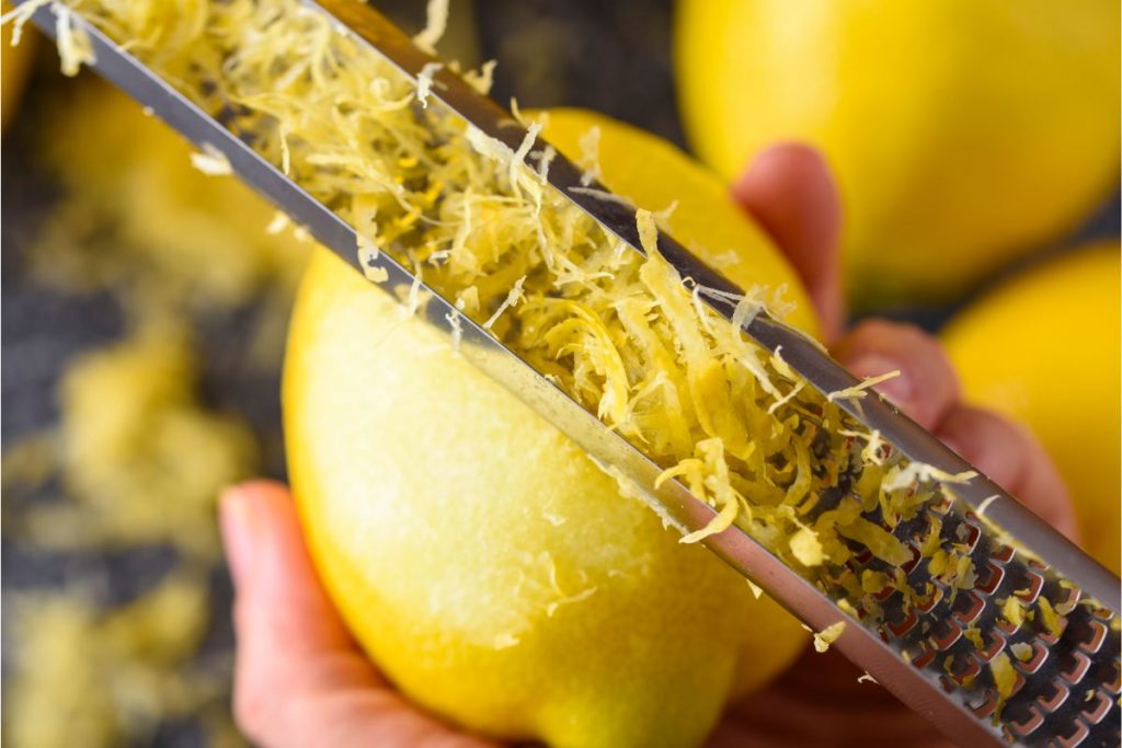 Woman using a microplane zester on a lemon peel