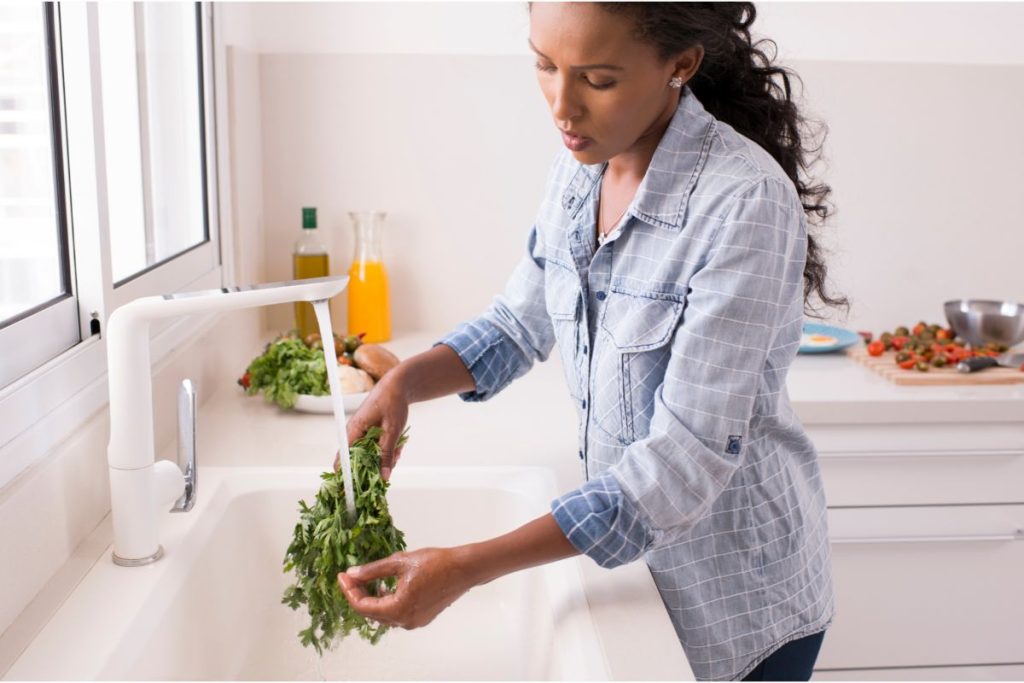 Woman washing parsley at a sink