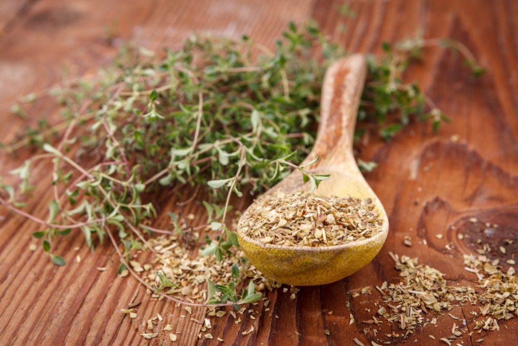 Dried thyme leaves in a wooden spoon