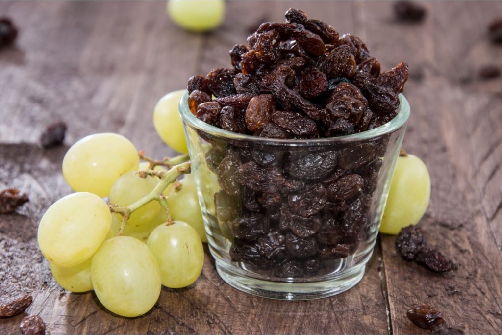 Shot glass of raisins surrounded by green Thompson grapes