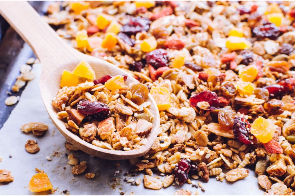 Dehydrated cereal grains and fruit pieces with a wooden spoon