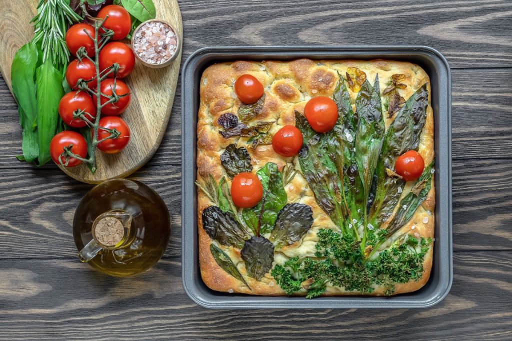 Focaccia bread with herbs, leaves and tomatoes made to look like a garden and baked into the top of the bread