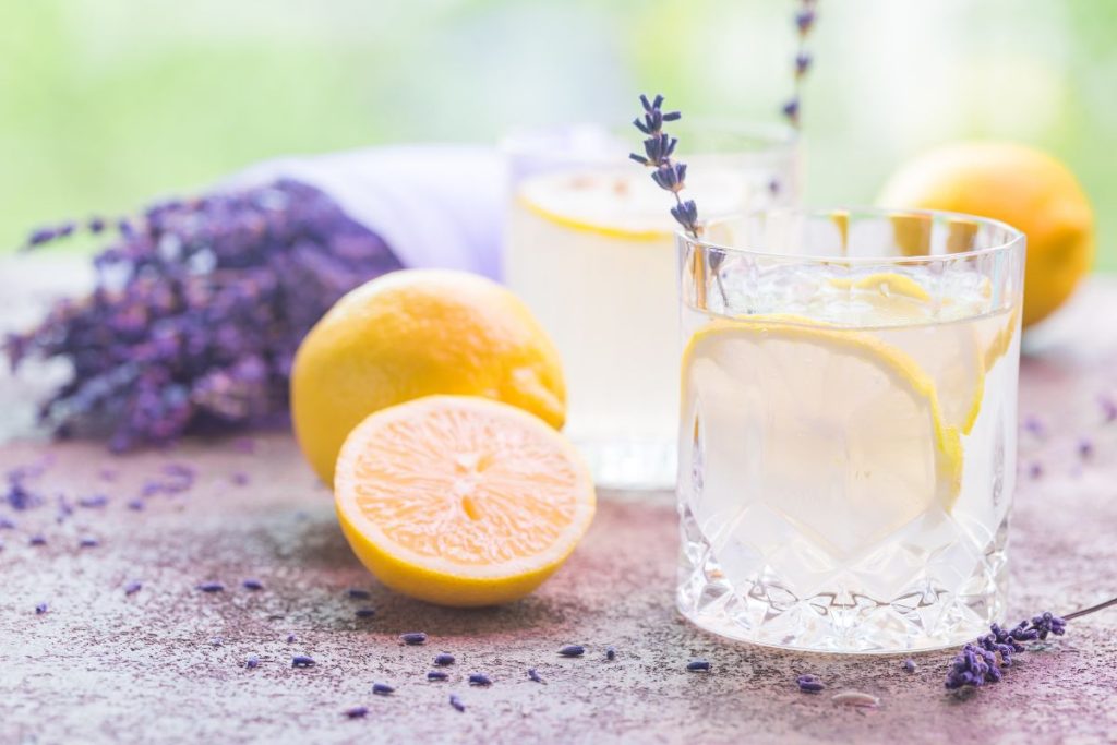 Glass of lavender lemonade surrounded by split lemons and lavender