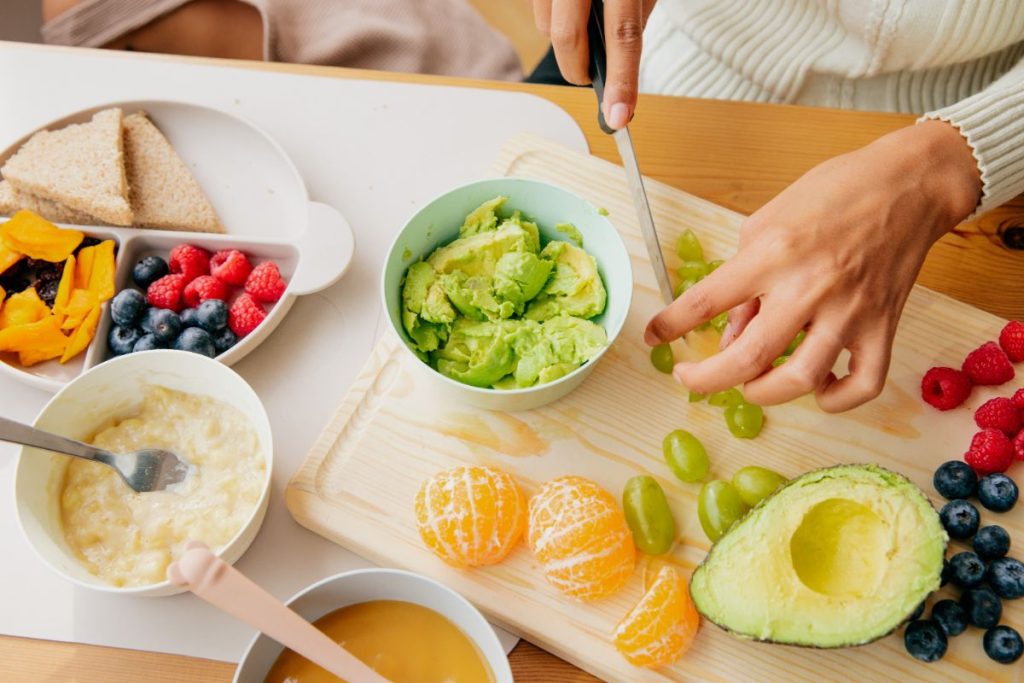 Woman cutting fruits on a cutting board to make baby food